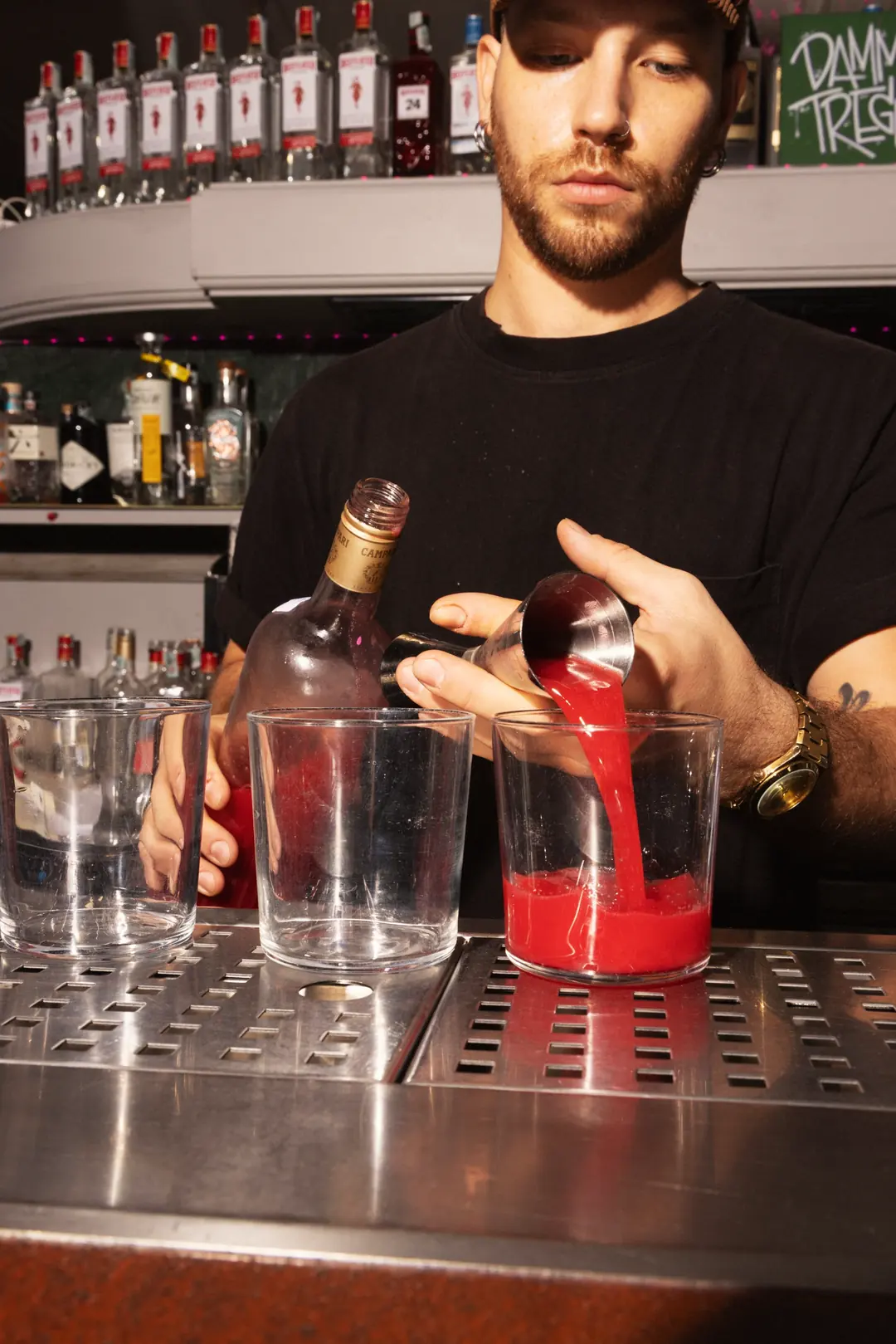Il barman versa un cocktail rosa al bancone